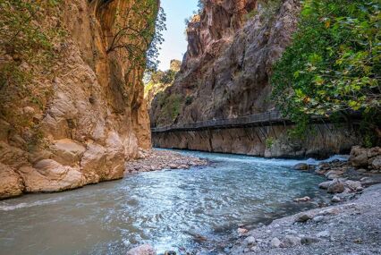 Beautiful river flowing at the bottom of the canyon, with a footbridge nearby