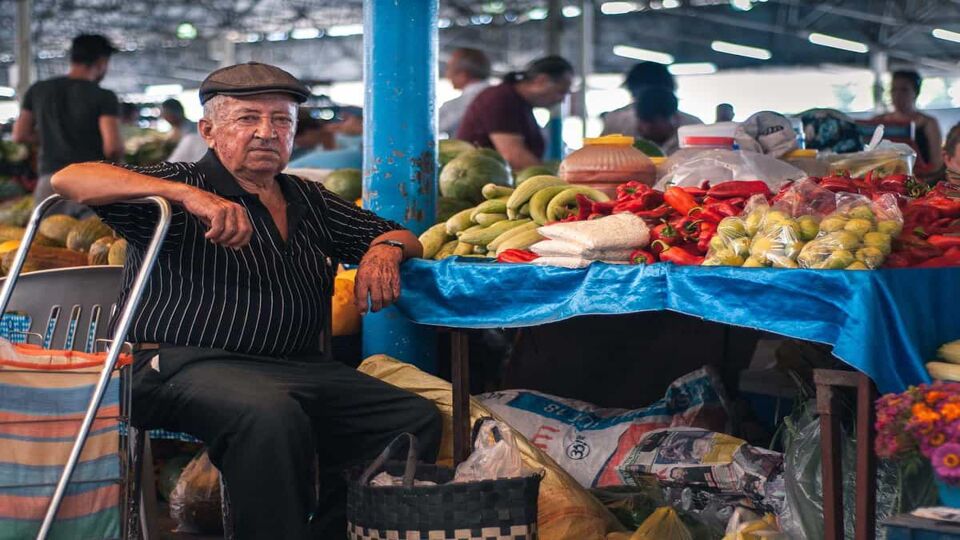 Elderly man in the open market sells fresh vegetables