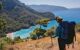 Man with backpack relaxing on top of a mountain and enjoying on view the bay and sea landscape