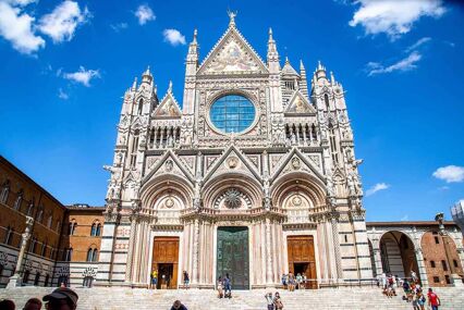The facade of the Siena Cathedral in the sunlight and the circular window