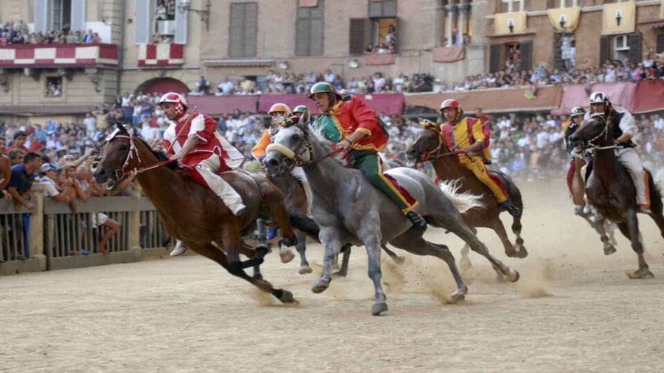 Horses racing around a track at il palio in Siena