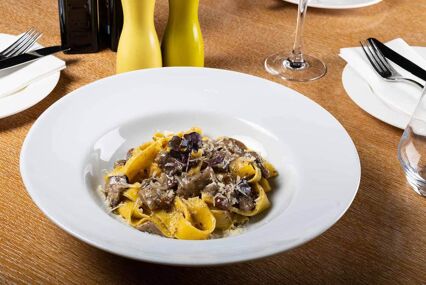 Fresh pappardelle pasta with porcini mushrooms and truffle scent. Traditional italian dish cooked in italian style and spices. Parmesan and mozzarella cheese sauce dressing.