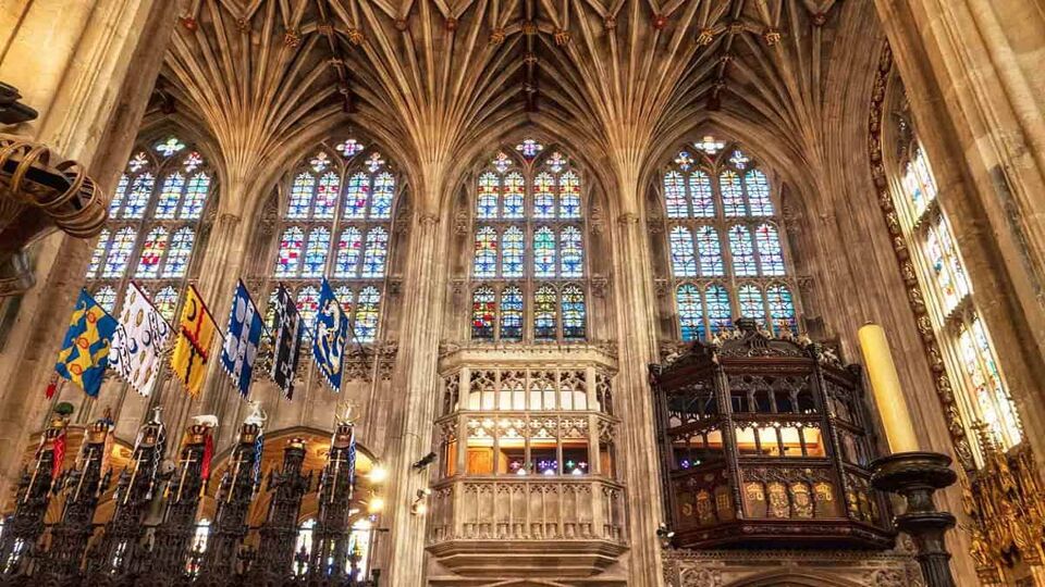 Interior of the medieval St George's chapel - Large elongated arched windows and rows of flags set in place in front of the windows. The host of prince William and Meghan Markle wedding ceremony in windsor, England UK .