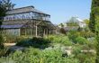 Large botanical greenhouse on a sunny day with bushes and plants in the foreground