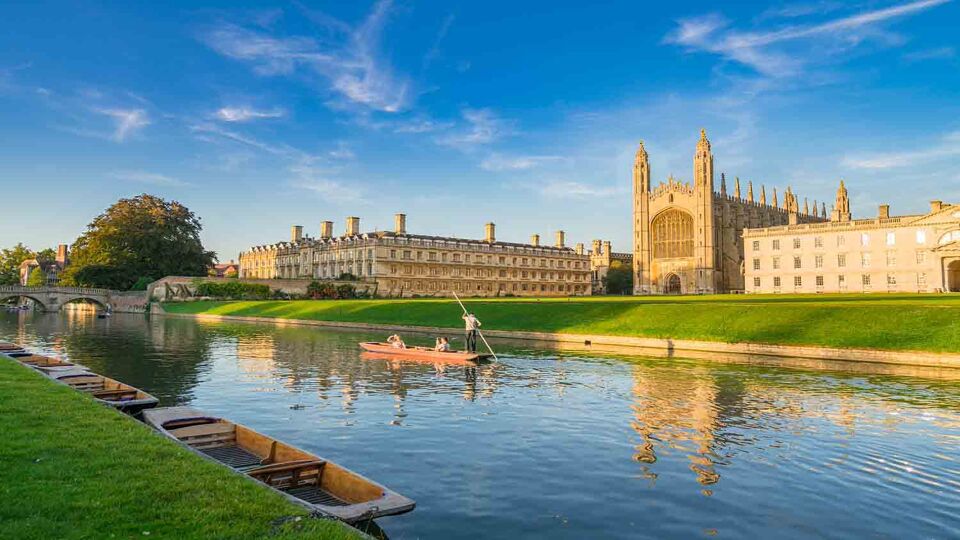 Beautiful view of college in Cambridge with people punting on river cam