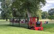 A toy train filled with tourists driving through the gardens