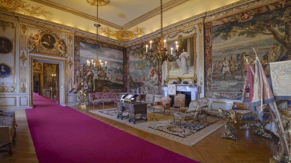 A room with a red carpet and lots of paintings