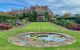 view down a lawn to the manor house. pond in foreground