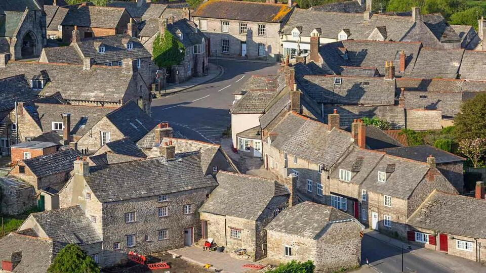 Architecture of the Corfe Castle village in County Dorset, UK. From this distance the houses look densely packed with each house looking almost identical with a similar tone of grey brickwork on the exterior and roofings