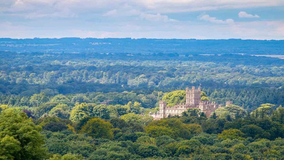 An elevated view of Highclere Castle taken from Beacon Hill. The castle can be seen peeking through the never ending woodlands