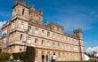 Low angle front view of Highclere Castle with a bright blue sky in the background