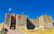 A front view of Henry II's Great Tower of Dover Castle in Kent. The castle has a rectangular and cubic structure with three different flags hung on the outside.