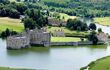 Birds eye view of Leeds Castle, where you it is surrounded by a castle and woodlands in the background
