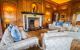 The interior of a room in Leeds castle where Henry VIII used it as a dwelling for his first wife, Catherine of Aragon in the 16th century. Four couches surrounding a fireplace with orange tinted lighting in the room