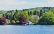 a small castle on shores of lake windermere surrounded by trees