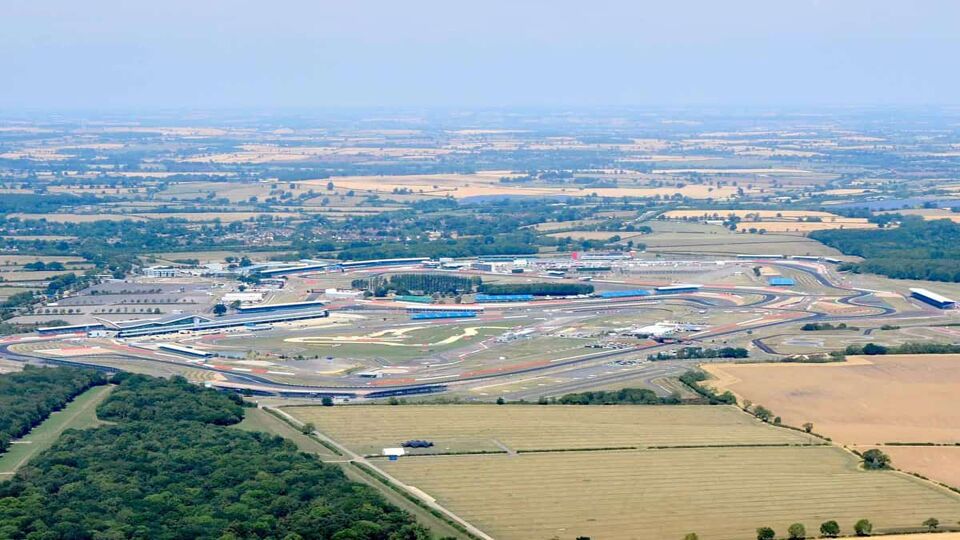 Aerial view of Silverstone Circuit surrounded by open green fields on a foggy day