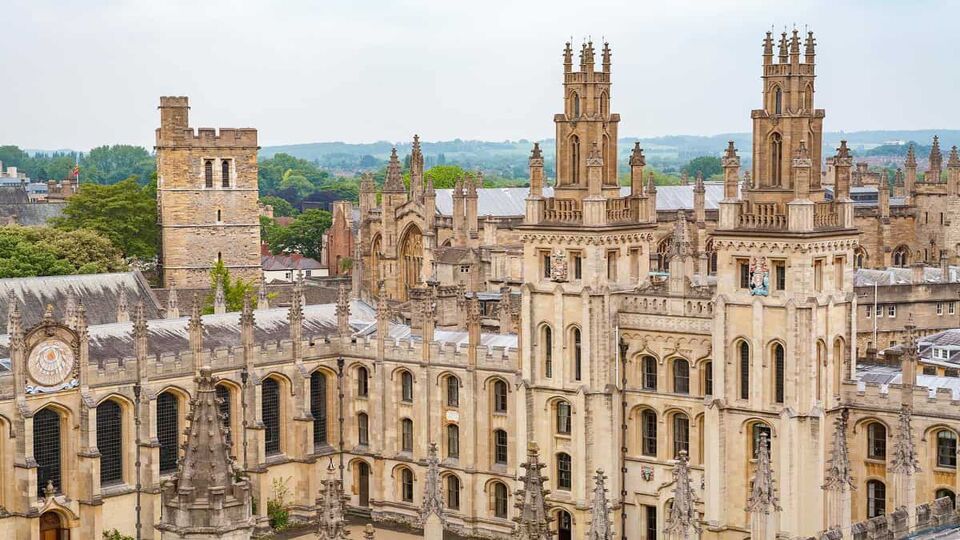 Aerial view of All Souls College. Intricate carved sandstone, with many narrow rectangular windows, and several decorative turrets.