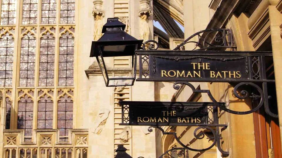 Iron signs for the Roman Baths of Bath England in front of the Abbey