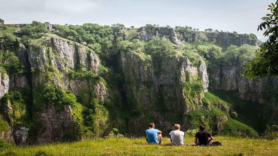 two people in a field staring at Cheddar Gorge