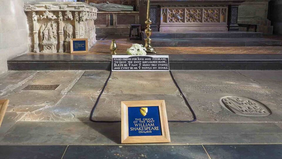 Grave of William Shakespeare in Holy Trinity Church with a black headstone and a frame of Shakespeare's name on the foreground
