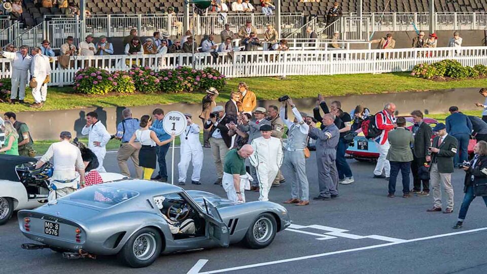 E-Type Jaguar (179), Aston Martin (6), and Ferrari (11) line up on the grid for the Kinrara Trophy (Revival) with the team and photographers in vintage clothing.