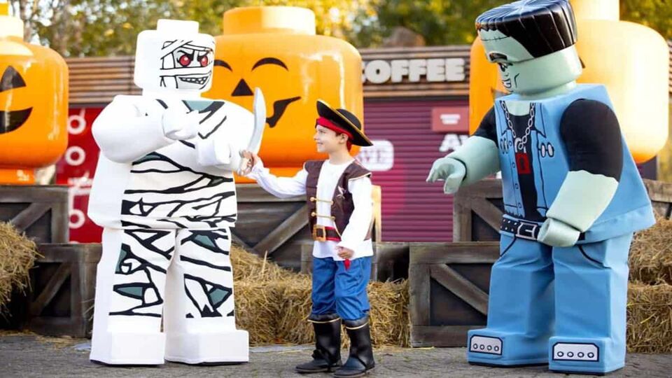 A boy dressed as a pirate, posing next to two Logo mascots