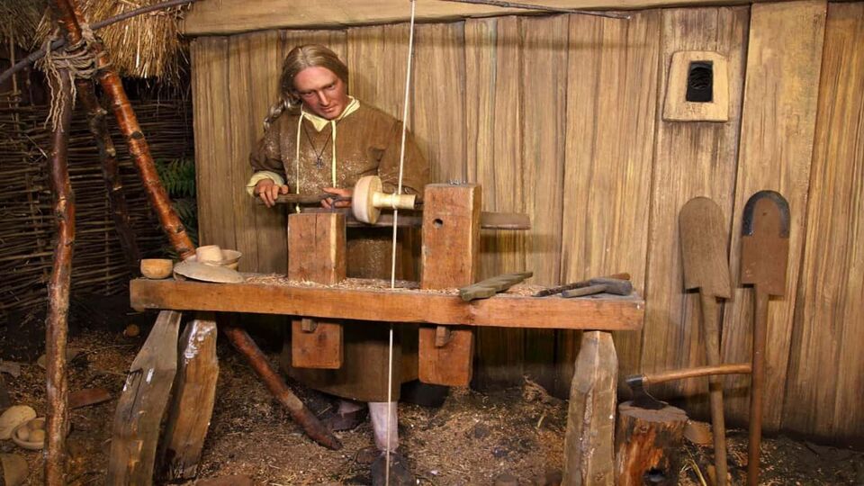 Mannequin in a museum showing a man working with wooden tools