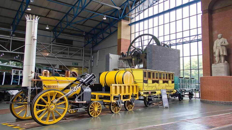 Yellow first-class railway coach attached to steam locomotive