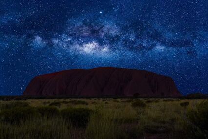 Many stars over the silhouette of a flat mountain.