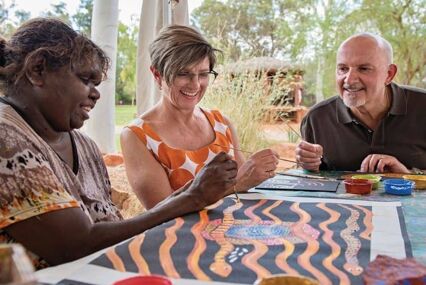 3 people dot painting at the Maruku Arts Centre on Uluru