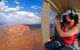 A woman taking a photo of Uluru from the back of a helicopter