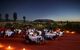 People dining on linen covered tables at sunset outdoors, with the backdrop of the desert