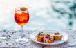 Spritz Aperol drink with venetian traditional snacks cicchetti on the water chanal background in Venice. Traditioanal italian aperitif. Image with small depth of field