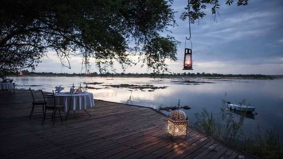 A romantic table set out on the wooden decking looking across the water