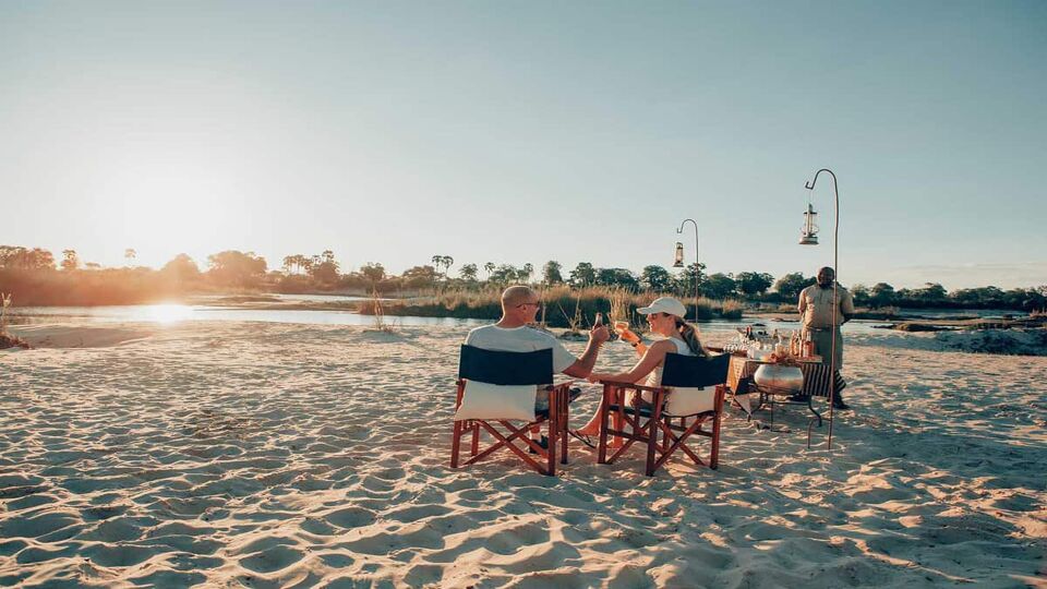 Couples enjoying the sunset from chairs on the sand