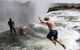 Man jumping into Devil's Pool right on the lip of the falls