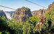 Man smiling on zip-line across the Zambezi with the Victoria Falls Waterfall in the backdrop