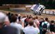 Crowd watching racing car whizzing around a track