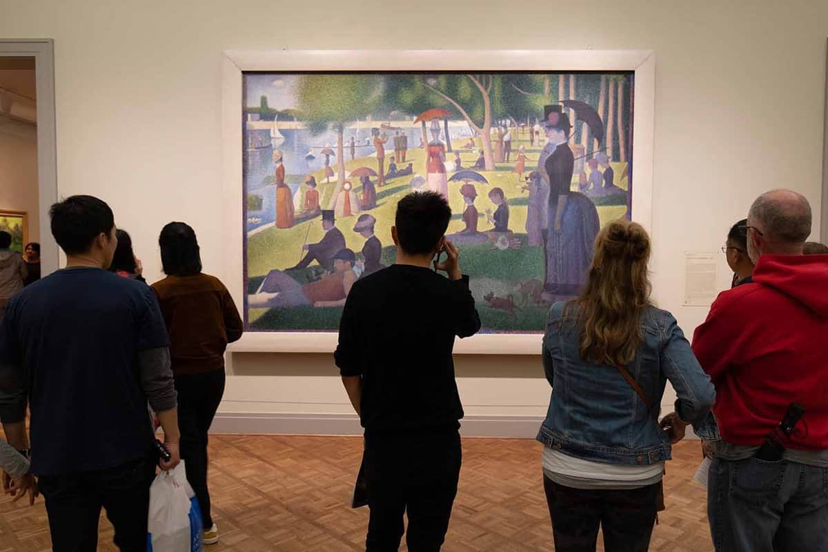 : People watching a painting at a museum