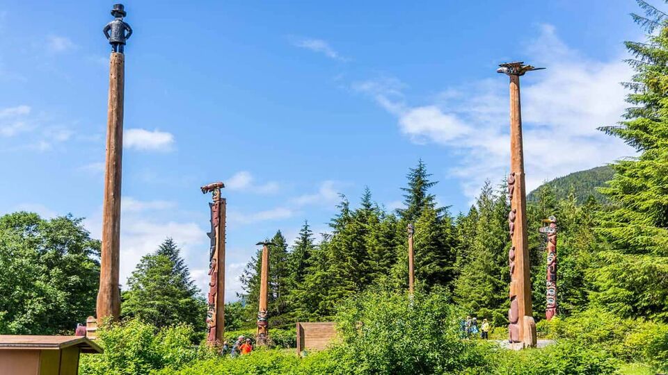 5 very high poles with carvings on amidst the trees