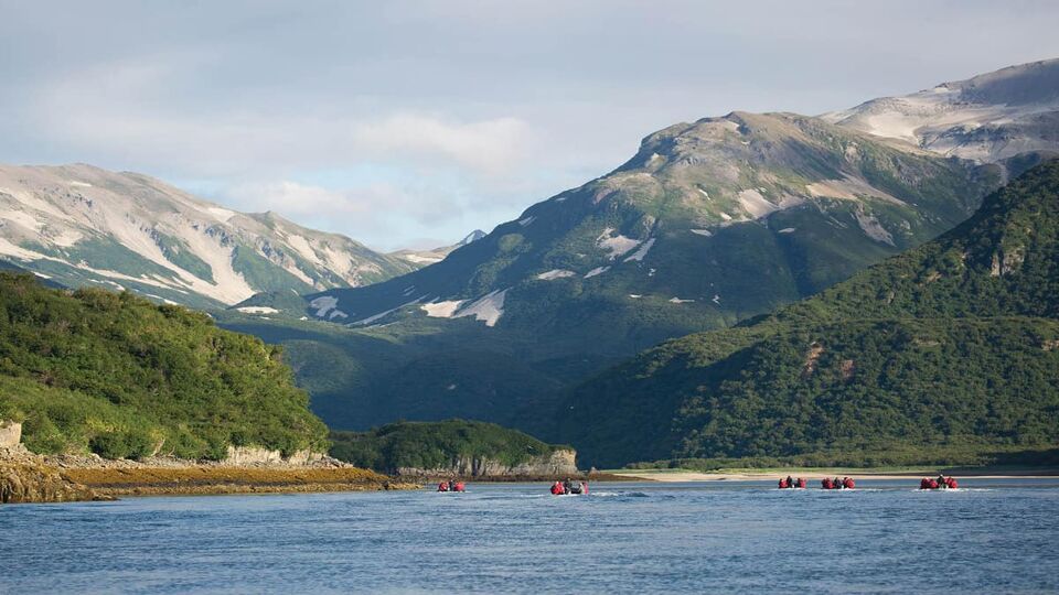 view of kayaks on sea with mountains behind