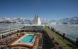 Rear of cruise ship deck, pool in foreground, iced mountains in background