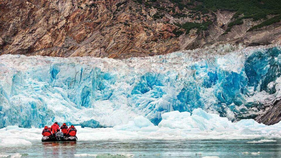 people on a zodiac up close to a glacier