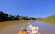 two tourists sitting at front of a canoe going along the river