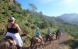 cruise passengers horse riding down a mountain trail