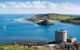 lovely landscape view of a small castle with blue sea and hills behind