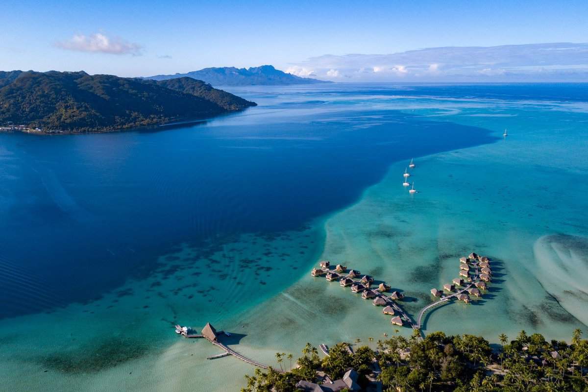 landscape of blue sea, mountains and some overwater bungalows