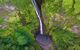 An aerial view looking down on it to a small pool amidst trees