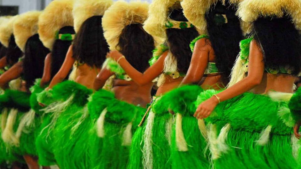 A line of dancers from behind dressed in traditional green dresses