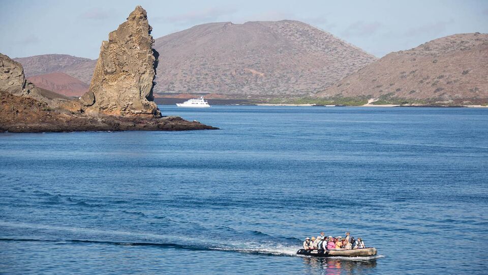 Guests exploring Bartolomé Island on a zodiac. big pointed rock sticking up in background